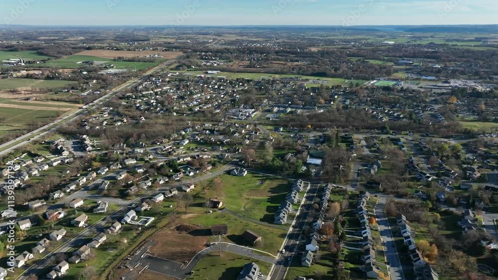 Aerial establishing shot of rural landscape with American housing area and busy interstate highway in Elizabethtown, Pennsylvania. Wide shot. Farm fields during sunset time. Aerial establishing shot of rural landscape with American housing area and busy interstate highway in Elizabethtown, Pennsylvania. Wide shot. Farm fields during sunset time.