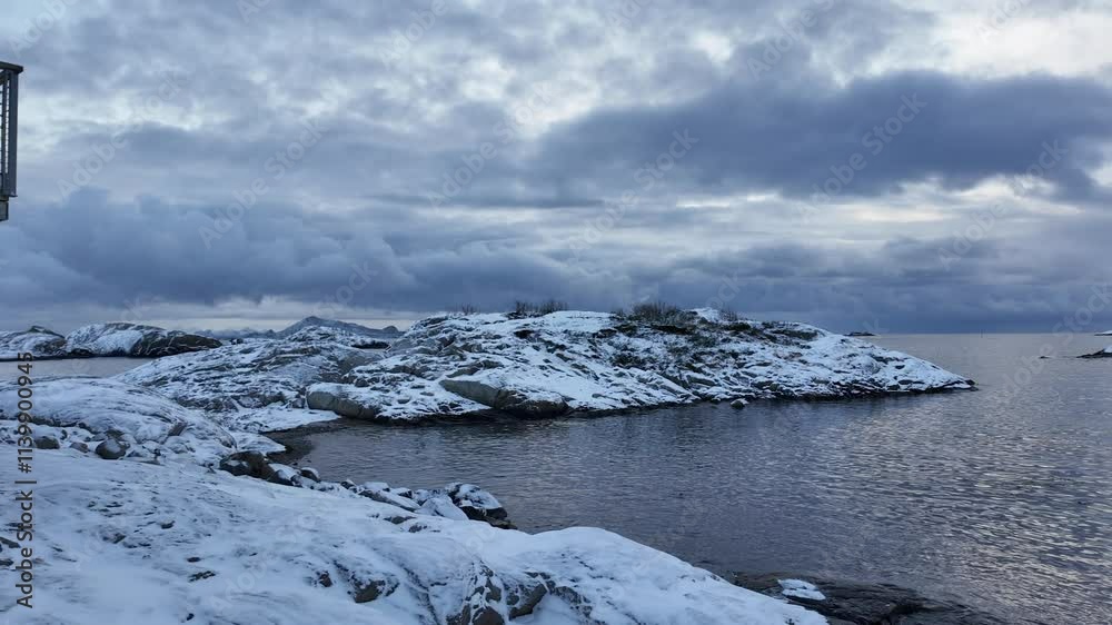 Snowy shore in Svolvear, Norway, with calm waters and serene winter sky Snowy shore in Svolvear, Norway, with calm waters and serene winter sky
