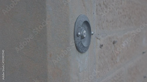 Closeup footage of an adult hand pressing the doorbell button on a stone wall, during daytime