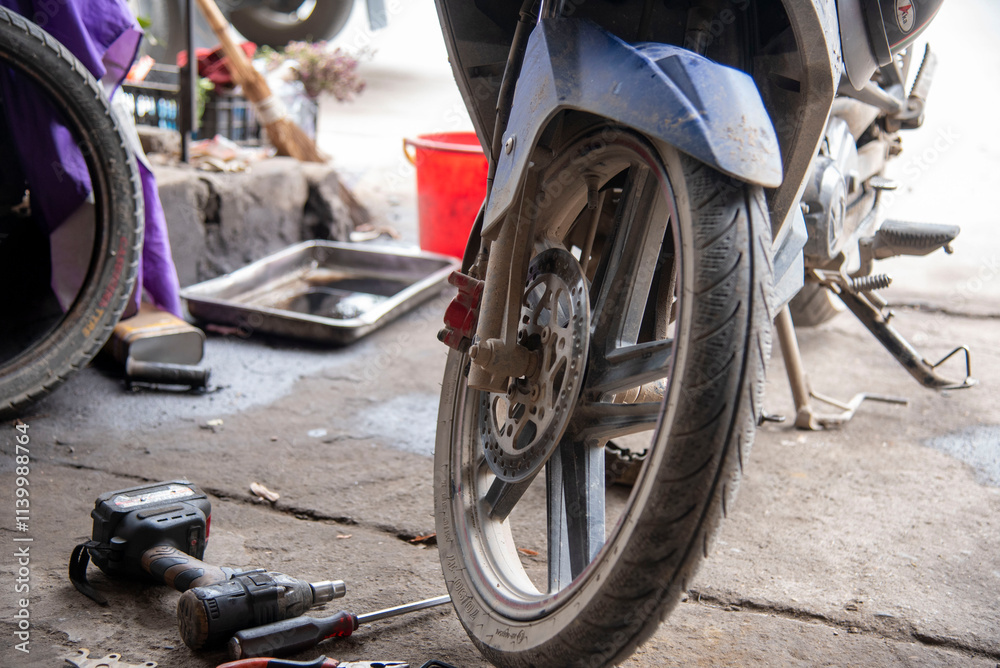 Mechanic sitting focused using wrench to repair motorcycle brake, drum brake pads at repair shop Mechanic sitting focused using wrench to repair motorcycle brake, drum brake pads at repair shop