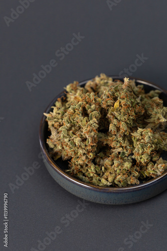 in a bowl dry flowers of medical cannabis on a black background