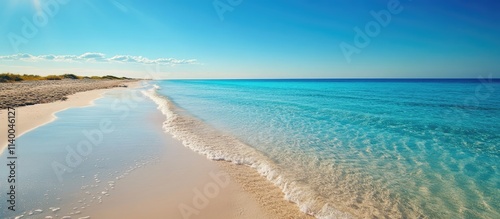 Tranquil clear water beach with gentle waves and a vibrant blue sky on a serene island coastline