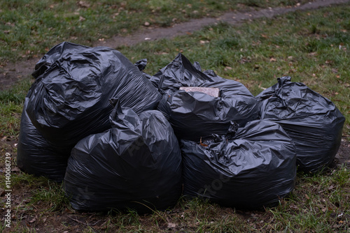 A group of black garbage bags piled together on grass