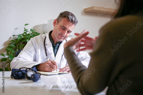 A male doctor consulting in his private office and reviewing patient reports.