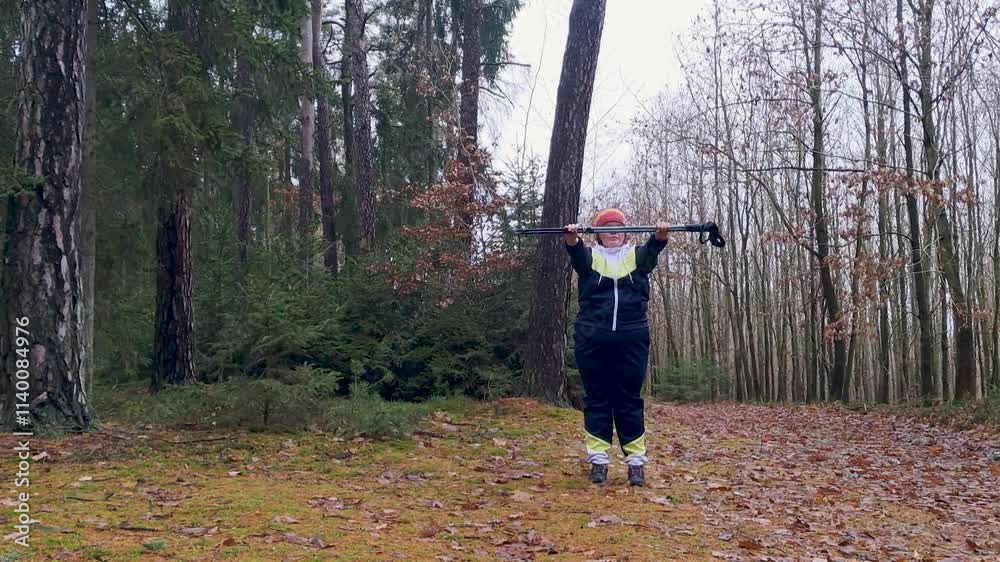 A plus-size woman training with Nordic walking poles in an autumn forest. A plus-size woman training with Nordic walking poles in an autumn forest.