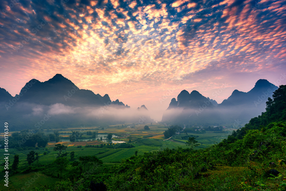 Obraz premium Landscape of vibrant sunrise over mountain range with foggy, river and traditional village in Phong Nam Valley