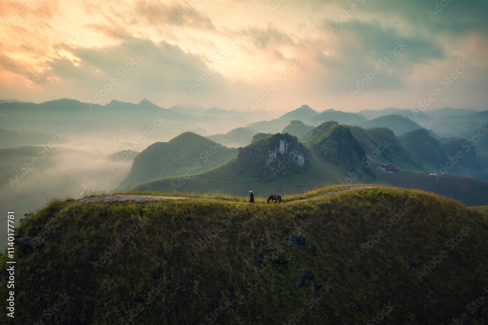 Scenery of Ba Guang grass hill, Mountain range with fog and villager bringing horse to graze on the mountain in the morning Scenery of Ba Guang grass hill, Mountain range with fog and villager bringing horse to graze on the mountain in the morning