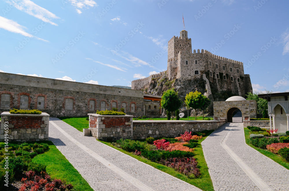 Obraz premium Historic Rabat Castle with Golden Dome, White Arches, and Lush Gardens Featuring Fountains Pools and beautiful colorful flowers surrounding old wall