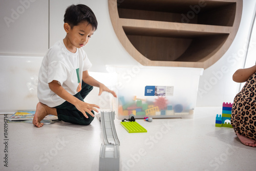 Kindergaretn asian boy enjoying play building colorful toy block in school