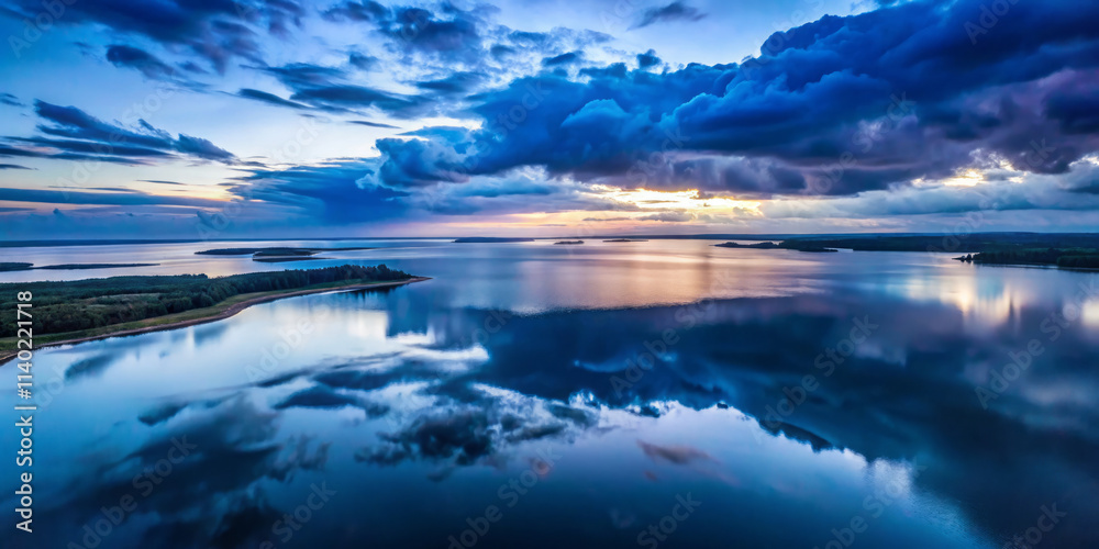 Fototapeta premium serene aerial view of tranquil body of water reflecting dramatic clouds at sunset, showcasing beauty of nature colors and calmness