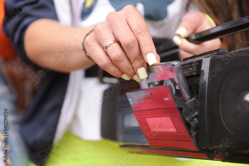 The girl inserts a cassette into the tape recorder.