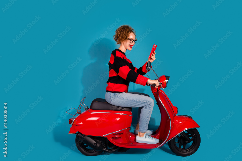 Young woman on a red scooter taking a selfie with blue background and striped sweater Young woman on a red scooter taking a selfie with blue background and striped sweater