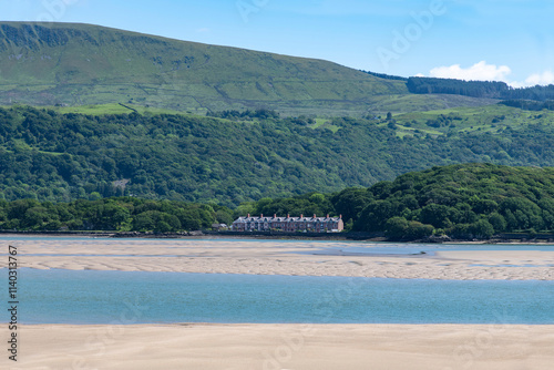 Panoramic view over sandbanks in the Mawddach Estuary and Afon Mawddach river with row of townhouses in hills against a white clouded blue sky photo