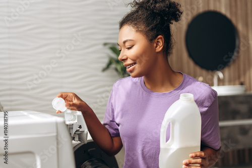 Housewife pouring washing pod and liquid detergent into washing machine photo