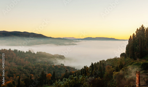 Tuscany countryside awakening with fog covering the valley at sunrise