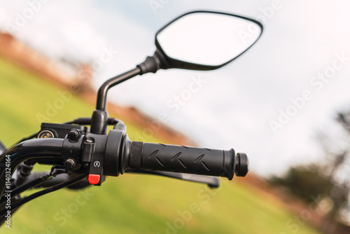 Black motorcycle rearview mirror and motorcycle handlebar on a sunny day of travel