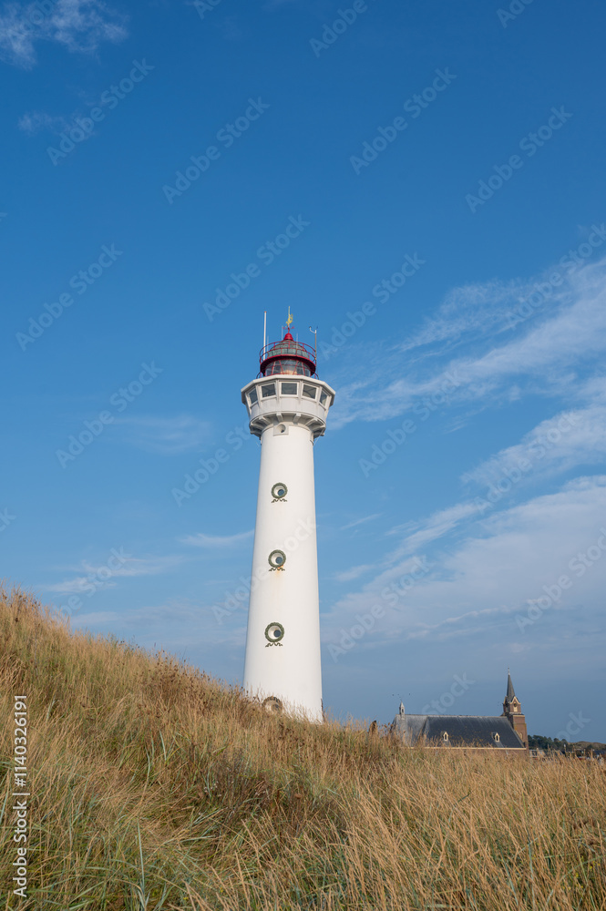 Lighthouse in the Dutch town of Egmond aan Zee with a church and sand dune Lighthouse in the Dutch town of Egmond aan Zee with a church and sand dune