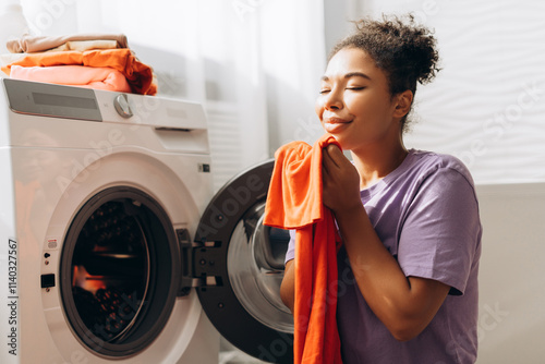 Billede på lærred Housewife smelling fresh laundry by washing machine