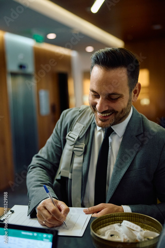 Happy businessman writing his data in application form at reception desk in gym. photo