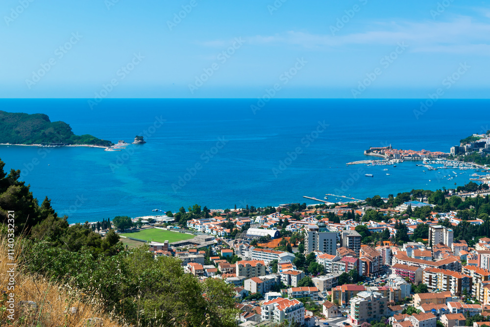 Naklejka premium Panoramic landscape of resort Budva city on blue sky background. Top view. The architecture of the old and new city, located on Adriatic coast. Montenegro.
