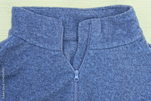 part of one grey wool jumper with open zip collar lies on yellow table in room photo