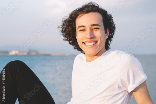 Cheerful hipster male admiring sunny day on city seashore photo