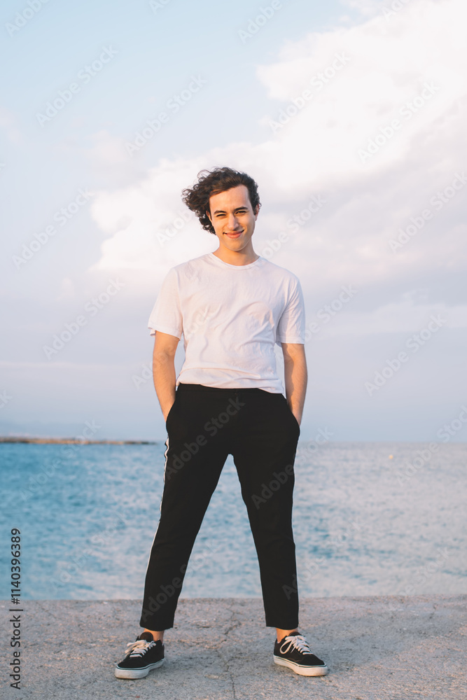 Young man standing on fence and looking at camera Young man standing on fence and looking at camera