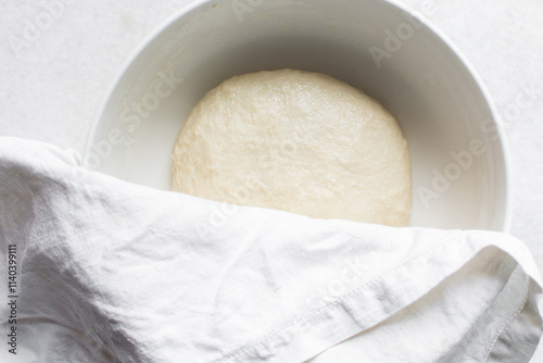 Overhead view of challah dough in a white mixing bowl, top view of homemade challah dough rising in a white mixing bowl, process of making challah photo