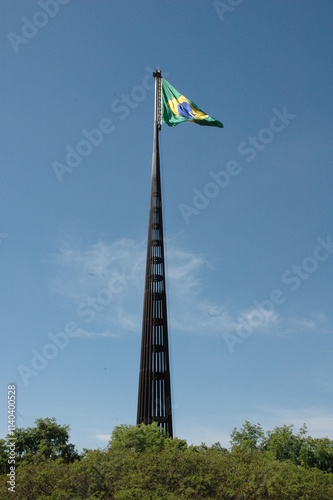 Brazilian flag on flagpole, blue sky background