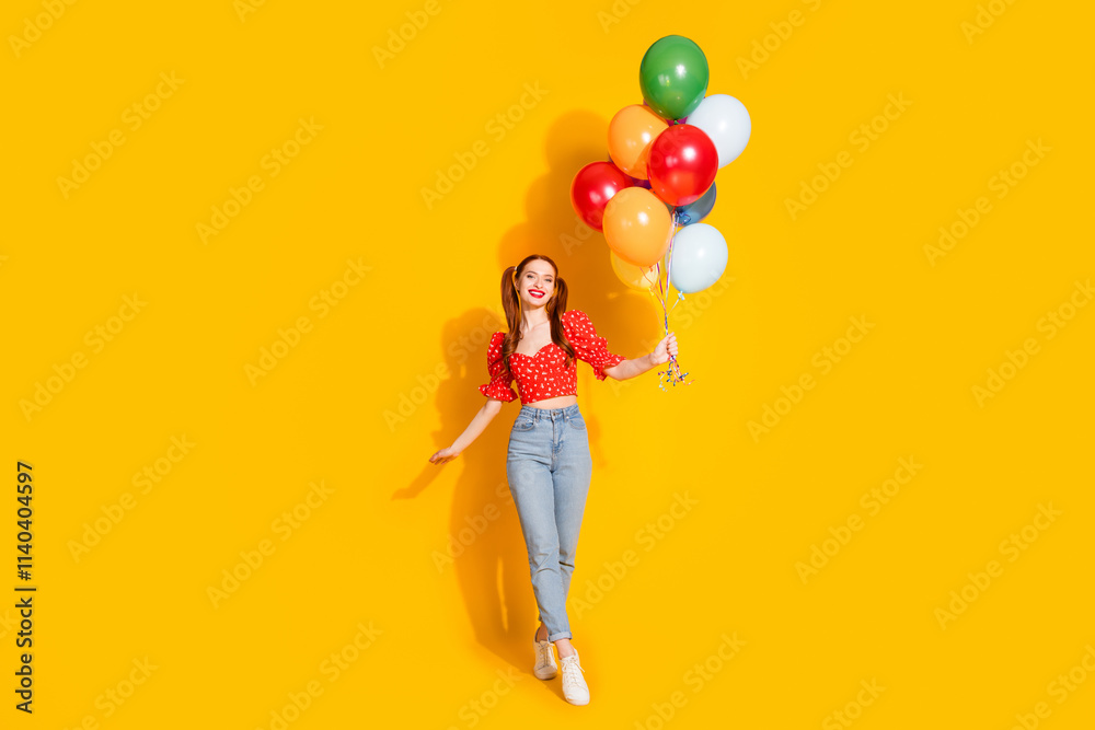 Full body photo of attractive young woman hold air balloons prepare holiday dressed stylish red clothes isolated on yellow color background Full body photo of attractive young woman hold air balloons prepare holiday dressed stylish red clothes isolated on yellow color background