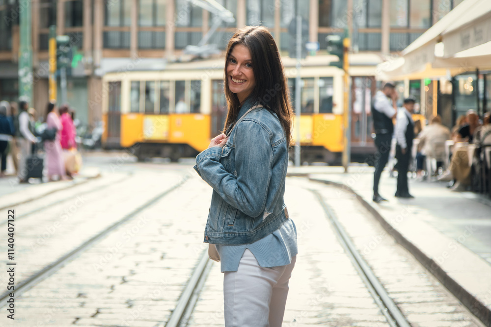 Fototapeta premium Attractive smiling woman posing while looking at camera in the middle of the street