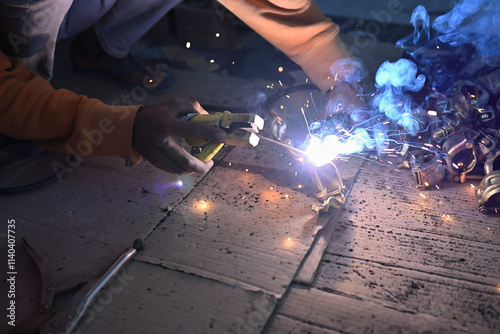Construction worker is doing welding work with the flaming sparks.
