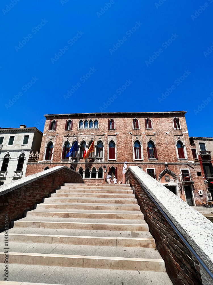 Fototapeta premium Historic brick building with stairs under clear blue sky. Venice, Italy.