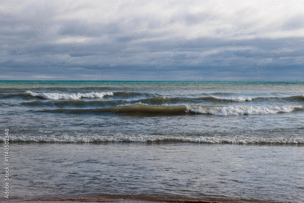 Strong, pounding incoming waves of Lake Michigan in mid-November crash near shore at Harrington Beach State Park, Belgium, Wisconsin under dark strorm clouds Strong, pounding incoming waves of Lake Michigan in mid-November crash near shore at Harrington Beach State Park, Belgium, Wisconsin under dark strorm clouds