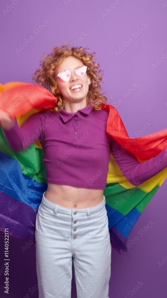 Young activist with rainbow flag on purple background in slow motion