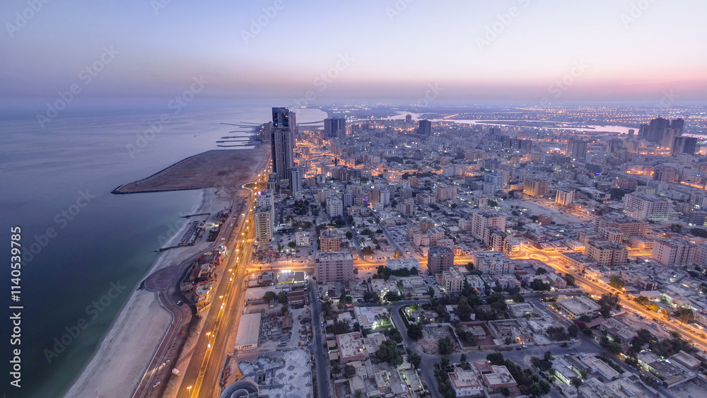Fototapeta premium Cityscape of Ajman from rooftop night to day timelapse. Ajman is the capital of the emirate of Ajman in the United Arab Emirates.