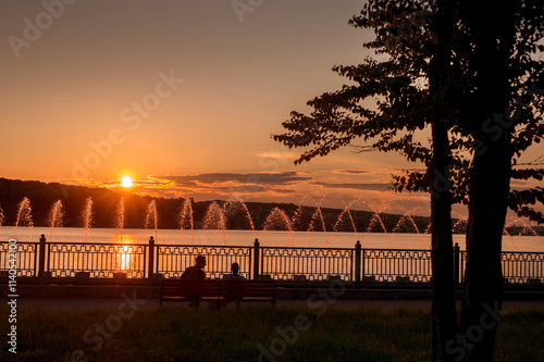 beautiful embankment of Ternopil Pond with fountains, silhouettes of trees an...
