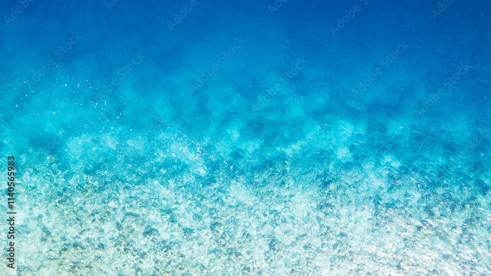 Top view of the turquoise gradient color of the water. The ocean is like a background. Incredible gradient from light blue to dark. Reef and fish swim. Clear water in the lagoon. The drone. Maldives