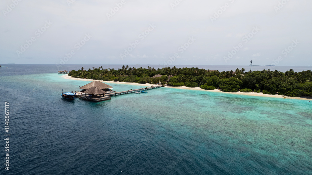 Top view of the bungalow on the water. Maldives. Luxury villas near the green island. The view from the drone. Turquoise water, beautiful reef. The rays of the sun on the surface of the ocean. Waves