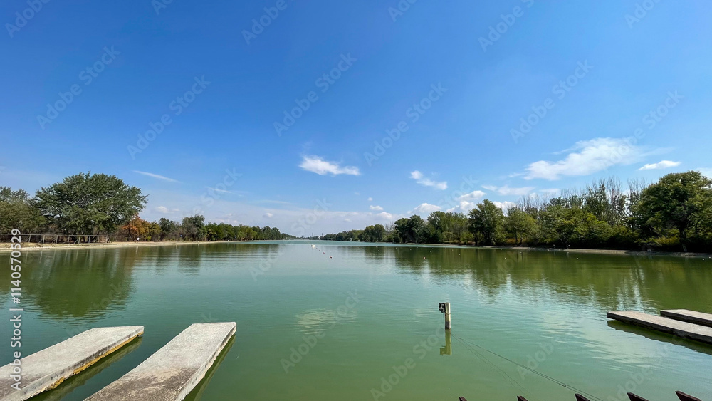 Concrete piers extending into a calm green lake under a clear blue sky, perfect for themes of nature, relaxation, and travel destinations. Concrete piers extending into a calm green lake under a clear blue sky, perfect for themes of nature, relaxation, and travel destinations.