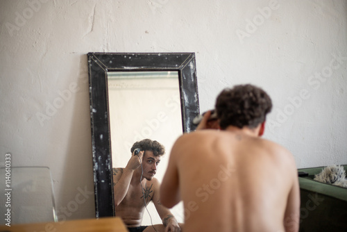 Man shaving head reflected in mirror, focusing on self-grooming photo