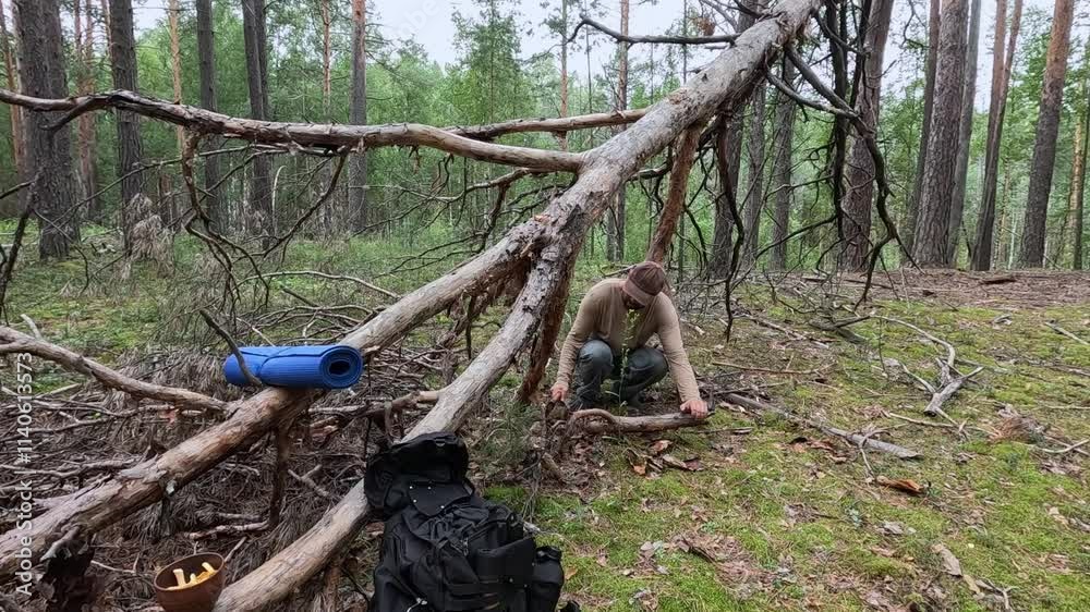 A man sawing a stick with a handsaw in the forest A man sawing a stick with a handsaw in the forest