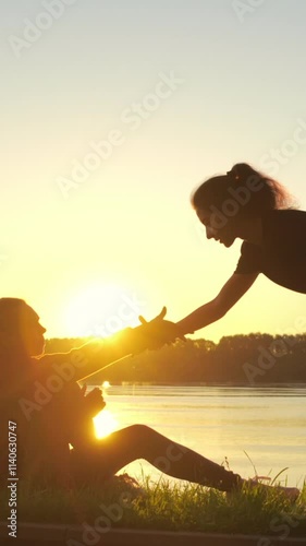 Silhouette of girl giving helping hand to her friend during training. Woman supports and helps another sportsman with trauma or health problems after running. Mutual assistance and teamwork in sport.