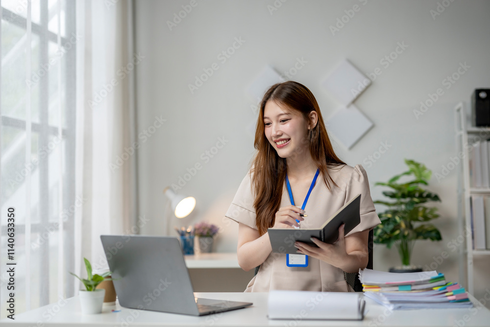 A woman is sitting at a desk with a laptop and a book A woman is sitting at a desk with a laptop and a book