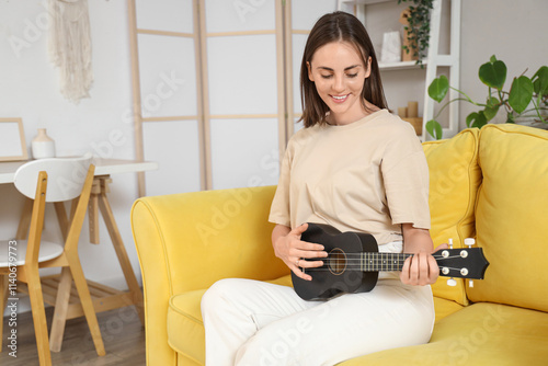 Young woman playing ukulele...