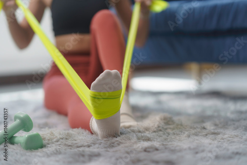 Close up of a woman's foot engaging with a resistance band during an invigorating home workout, emphasizing strength and flexibility training