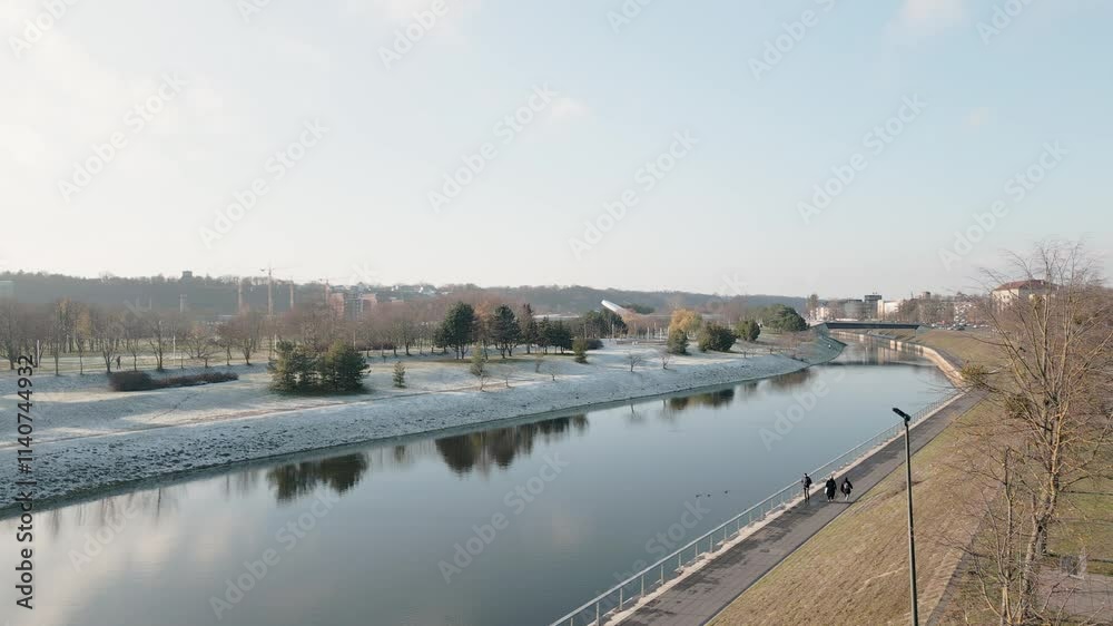 Static view Neman, Niemen or Nemunas river in Kaunas city and flows through Lithuania. Pedestrians walk along river in sunny winter day outside Static view Neman, Niemen or Nemunas river in Kaunas city and flows through Lithuania. Pedestrians walk along river in sunny winter day outside