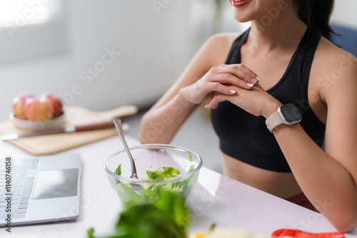 Smiling sportswoman enjoying a healthy salad after a workout, following a balanced diet and active lifestyle photo