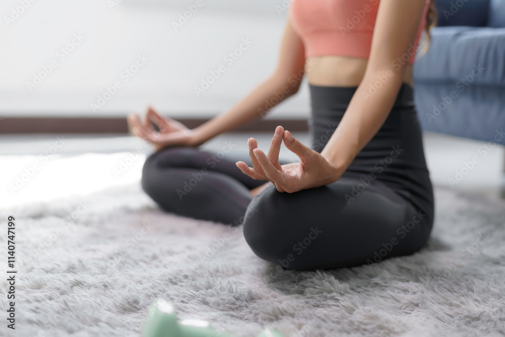 Naklejka premium Woman meditating in lotus position on a gray carpet, enjoying a moment of mindfulness and relaxation