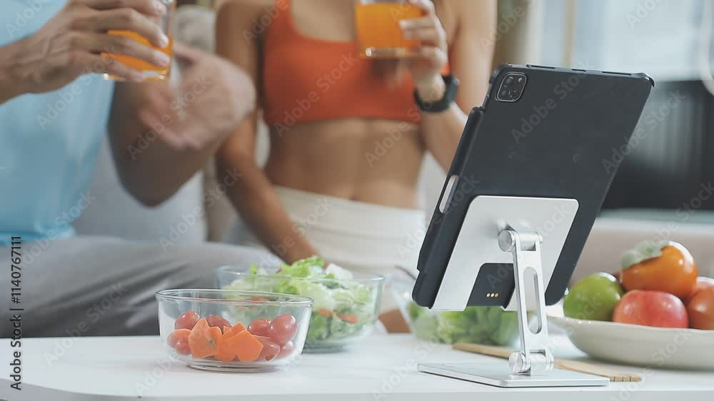 Nutritionist is giving online dietary advice to a client, with fresh vegetables and a salad on the table in front of her